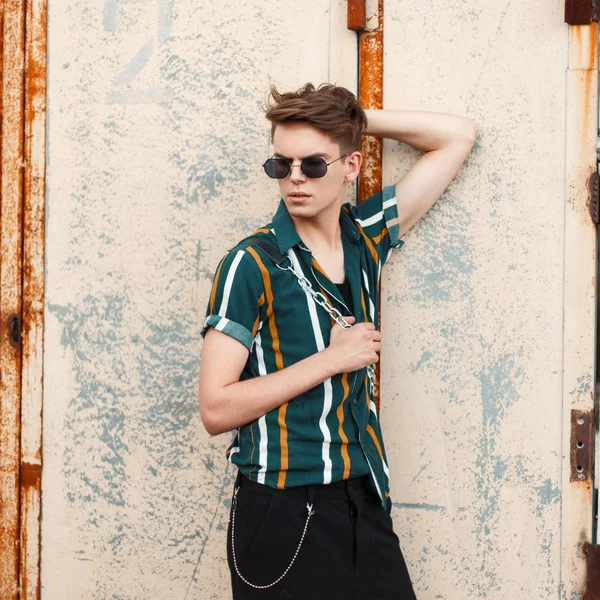 Paslı bir duvar sokak yakınındaki bir çanta gömlekli gözlüklü bir saç modeli ile şık yakışıklı genç adam
