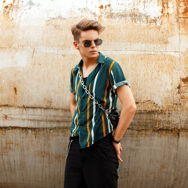 Bir metal paslı duvara yakın poz renkli moda gömlekli gözlüklü moda güzel model adam