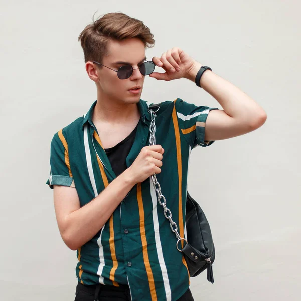 Yakışıklı olan yeşil duvar yakınındaki plajda plaj moda gömlekli gözlüklü