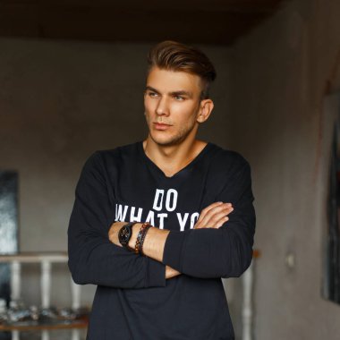 Şık yakışıklı genç bir siyah kazak beyaz yazı kapalı poz ile içinde