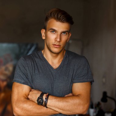 Gri bir T-shirt posi, bir saç kesimi ile şık yakışıklı genç adam