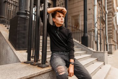 Siyah moda kazak yakınlarında bir evi var sokakta oturan kot ile erkekte moda yakışıklı modeli