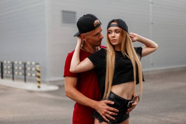 Moda yaz giysileri sokakta beyzbol kapaklar ile şık güzel genç çift