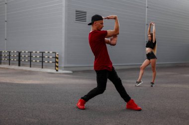 Sokakta dans bir kap ile Modern giyimleri şık yakışıklı hip-hop dansçısı. Seksi kız dansçı arka planda