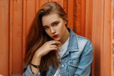 Metal bir turuncu duvarının yakınında sokakta bir moda kot vintage ceket şık güzel genç kız