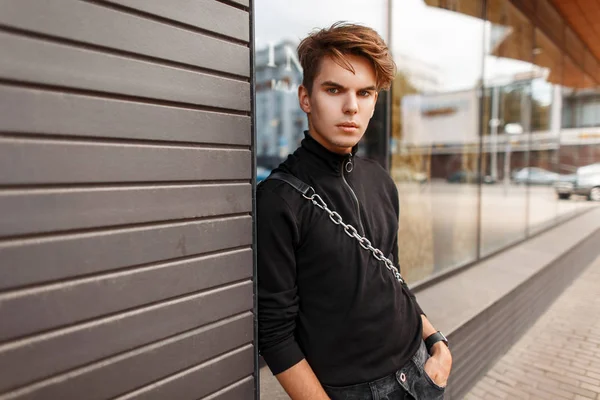 Elegante joven guapo en un jersey negro con una bolsa de pie — Foto de Stock