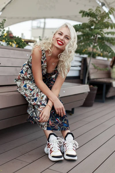 愉快的美丽的时尚模特女士与一个微笑的时尚礼服坐在板凳上 享受的时刻 — 图库照片