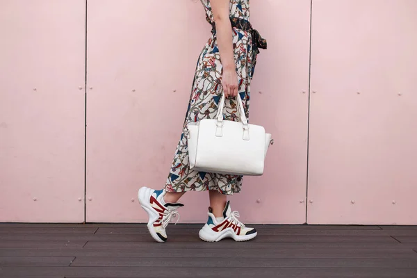 优雅时尚美丽的女孩在一个老式的礼服与白色时尚袋和运动鞋附近的粉红色墙 — 图库照片