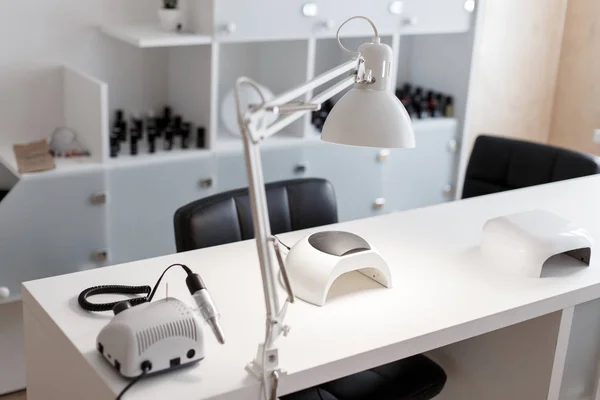 Manicure Studio. White lamp on white table with nail tool