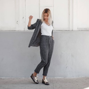 beyaz bir T-shirt gri bir ceket ve sokakta poz Ayakkabı gri şık pantolonlarla şık güzel genç kadın. Moda iş tarzı giysiler