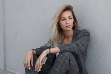 Duvara yakın sokakta oturan moda vintage gri elbiseli şık güzel genç model kadın