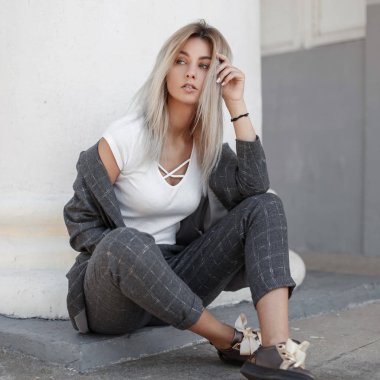 Moda güzel şık bir model kız ayakkabı ile gri şık elbiseli column yakınındaki sokakta oturuyor