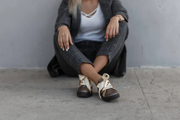 时尚的女孩在时尚的复古灰色西装与鞋坐在街道附近的灰色墙壁 — 图库照片