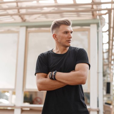 Siyah t-shirt sokakta Ahşap Bina yakın duruyor modeli erkek saç modeli ile şık yakışıklı genç moda