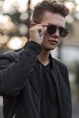 Şık güneş gözlüğü siyah şık giysilerle sokakta sabitleme genç yakışıklı bir adam portresi