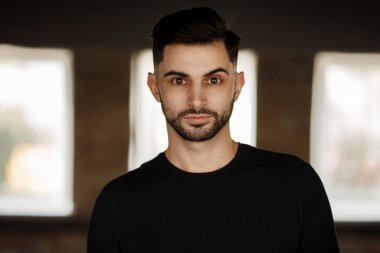 Bir şık yakışıklı genç bir sakal ve saç modeli Studio koyu arka plan siyah t-shirt ile portresi