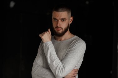 Beyaz karanlık bir arka plan üzerinde gri süveterli sakallı yakışıklı işadamı adam