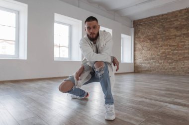 Yakışıklı çekici delikanlı sökük şık kot ve beyaz spor ayakkabı kameraya bakarak Studio poz ile moda ceket