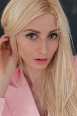 Yakın çekim şık siyah duvarının yakınında moda pembe elbiseli Pembe dudakları ile çiller ile genç ve güzel bir kadın portresi