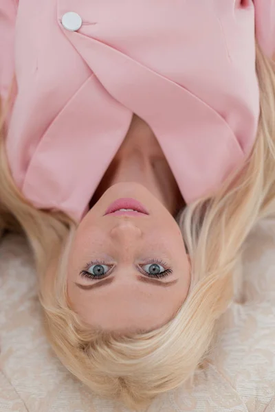 ソファの上面にあるピンクのおしゃれなスーツでそばかすのある美しい若い女性 — ストック写真