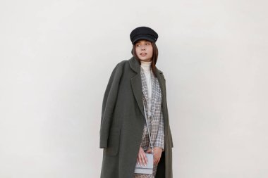 Damalı şık takım elbise ve duvara yakın poz çanta şık yeşil paltolu bir şapka ile moda kadın