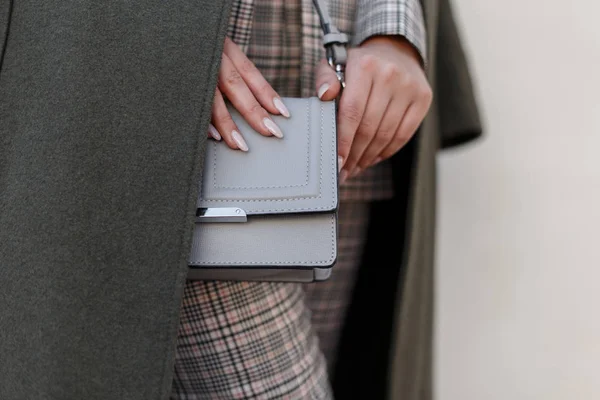 Beautiful women\'s fashionable gray handbag. Stylish young woman in a fashionable coat with a handbag. Close-up