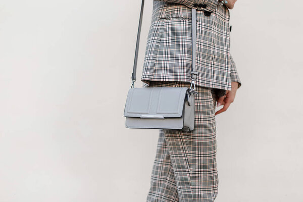 Fashionable women 's gray stylish handbag. Крупный план. Стильная молодая девушка в модной одежде в клетчатом костюме
