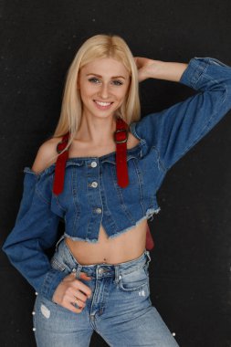 Neşeli güzel genç çekici mutlu kadın moda kot elbise siyah duvarın yanında mavi jeans ile bir gülümseme