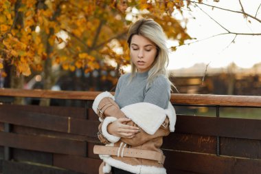 Güzel şık genç model kadın moda ceket gri bir kazak sonbahar park ahşap bir çit yakınlarında poz