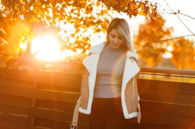 Bir şık örme vintage kazak ve gün batımında moda ceket keyfi sonbahar parkta güzel sevimli genç kadın. Sıcak güneşli bir çekici kız