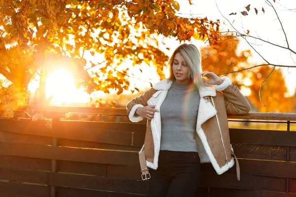 素晴らしいファッション金髪少女セーターとジャケットを黄金の木と明るい日光の近く楽しんでスタイリッシュなビンテージの秋服に 夕暮れの秋の女性 — ストック写真