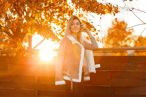 在一个秋天的傍晚 穿着时尚的秋装和毛衣和夹克的快乐快乐的年轻女子走在金色的公园里 女孩与美丽的微笑快乐在温暖的秋天阳光明媚的天 — 图库照片