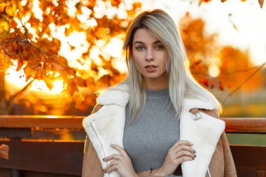 Güzel şık genç moda model kadın gri vintage kazak ve gün batımında ahşap bir çit sonbahar Parkı şık ceket. Moda kız 