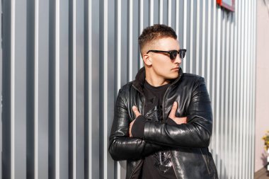 Yakışıklı şık genç hipster adam metal duvarın yanında moda gözlüklü siyah şık elbiseli