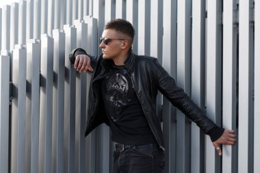 Siyah şık ceket ve metal duvarın yanında şık siyah kazak gözlüklü genç yakışıklı hipster adam