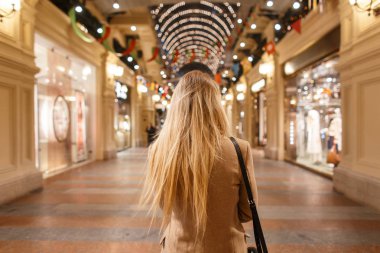 Şık genç kadın sarışın bir moda siyah çanta ile şık bir bej vintage ceket uzun saçlı alışveriş yürür ve şenlikli bir atmosfere sahiptir. Şık zarif kız.