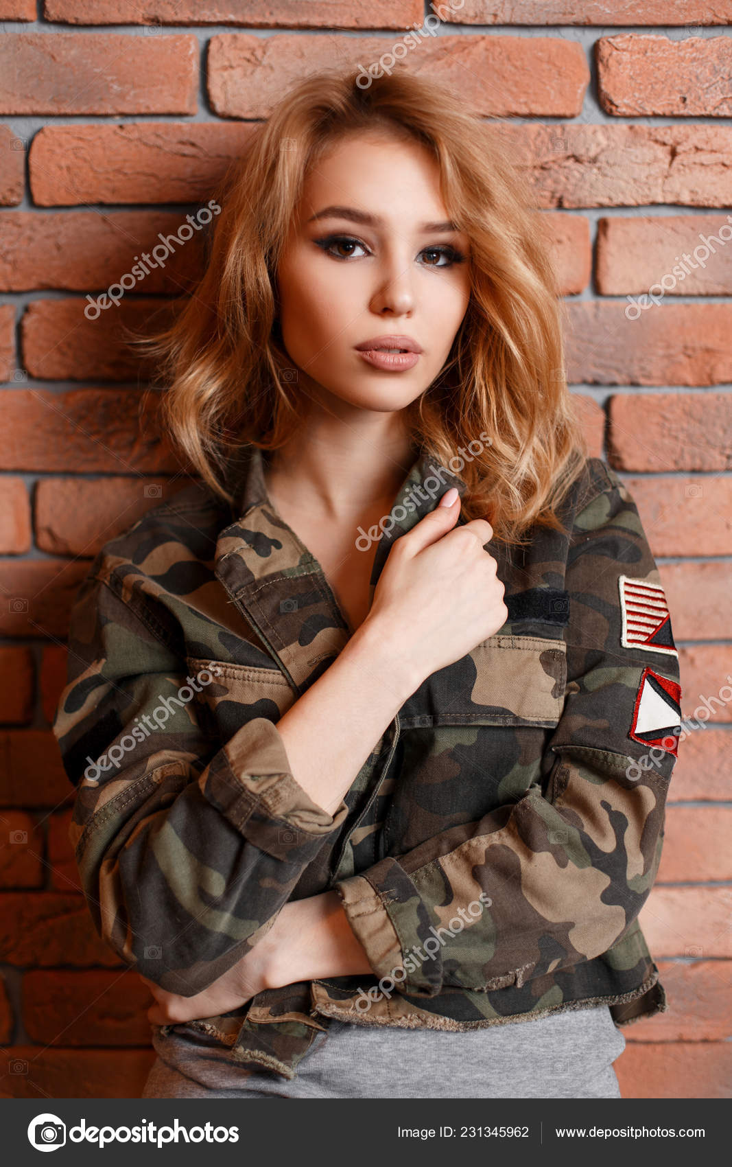 Hermosa mujer en chaqueta con estilo militar cerca de la pared de ladrillo