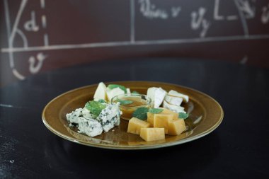 Parmesan peyniri ile mavi peynir ve tatlı bal, Gouda peyniri ile güzel kokulu fesleğen yaprakları ile süslenmiş. Lezzetli plaka. Büyük Aperatif. Peynir tabağı