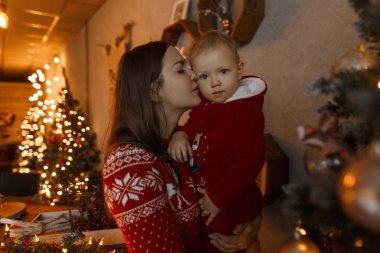 Örme kazak şık güzel annem ellerindetutan ve festival çelenk çerçevede şık peluş giysili küçük şirin çocuk öpücük. Mutlu bir kadın. Yeni yıl atmosfer