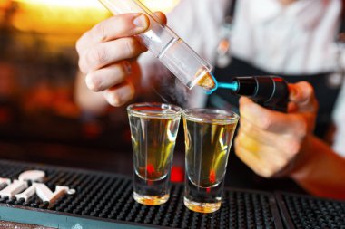 Barmen adam profesyonel bir yazıcı ile pub bar sıcak alkol çekim yapma. Barmen, bir bardak daha hafif ışıklar. Gece kulübünde rahatlayın. Sıcak ateş içer. Parti sağlar