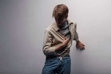 Örme Golf mavi moda pantolon teşkil yakınındaki beyaz bir duvar odadaki ışık vintage ceket şık bir saç modeli olan genç adam. Amerikan çekici şık adam. Bahar kıyafetleri