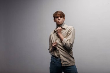 Avrupa yakışıklı genç hafif şık ceket gri örgü Golf beyaz duvarının yakınında bir odada poz şık bir saç modeli ile mavi şık pantolonlu. Şık şık adam