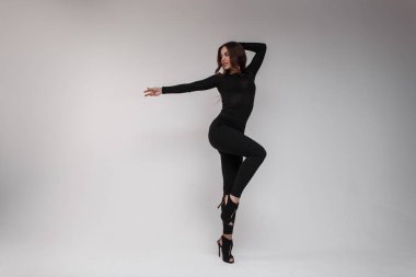 Şık tozluk ve onun topuklar üzerinde deri sandalet siyah şık şeffaf tişört güzel bir şekilde genç seksi çekici kadın parlak bir stüdyoda dans ediyor. İnanılmaz ince kız