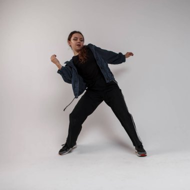 Güzel genç profesyonel dansçı kadınlar şık siyah bir T-shirt, kot pantolon beyaz bir arka plan üzerinde stüdyoda hip-hop dans spor. Yetenekli sevimli kız dans