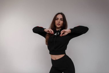 Çekici genç kadın dansçı bir şık siyah kazak siyah tozluk danslar modern dans aydınlık kapalı beyaz bir arka plan üzerinde kahverengi saçlı güzel. Moda sportif kız modeli