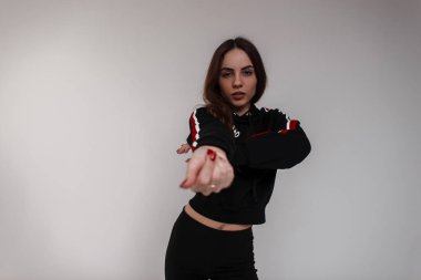 Şık siyah spor sweatshirt siyah pantolon beyaz arka plan için stüdyoda dans kırmızı ve beyaz çizgili bir genç çekici güzel kadın dansçı. Atletik güzel kız