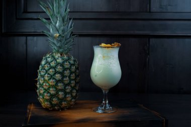 Tatlı beyaz sütlü alkollü kokteyl ile suyu buz küpleri ile ve kahverengi bir tabloda bir barda taze ananas yakınındaki votka tonik. Alkollü içecekler. Gece kulübü hayatı