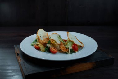 Bir kafede beyaz tabakta domates ve peynir dilimleri dilim beyaz ekmek kruton ve lezzetli hafif sosu ile güzel kokulu tavuk fileto ile diyet Sezar salata marul ile yaprakları