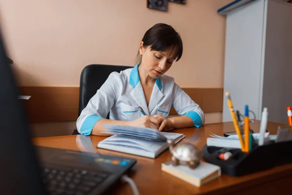 Uma Médica Uniforme Médico Branco Está Sentada Uma Mesa Madeira — Fotografia de Stock