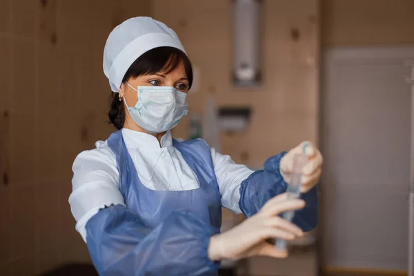 Pielęgniarka Białą Maskę Niebieski Odzież Medyczną Stoi Trzymając Strzykawkę Jej — Zdjęcie stockowe